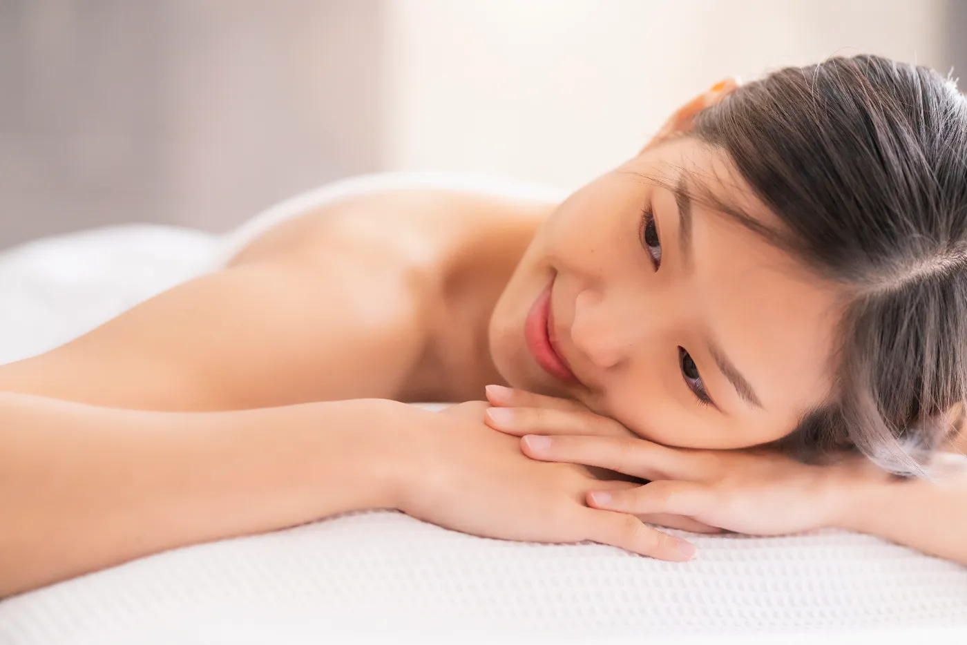 Relaxed Asian woman lying on a white spa bed