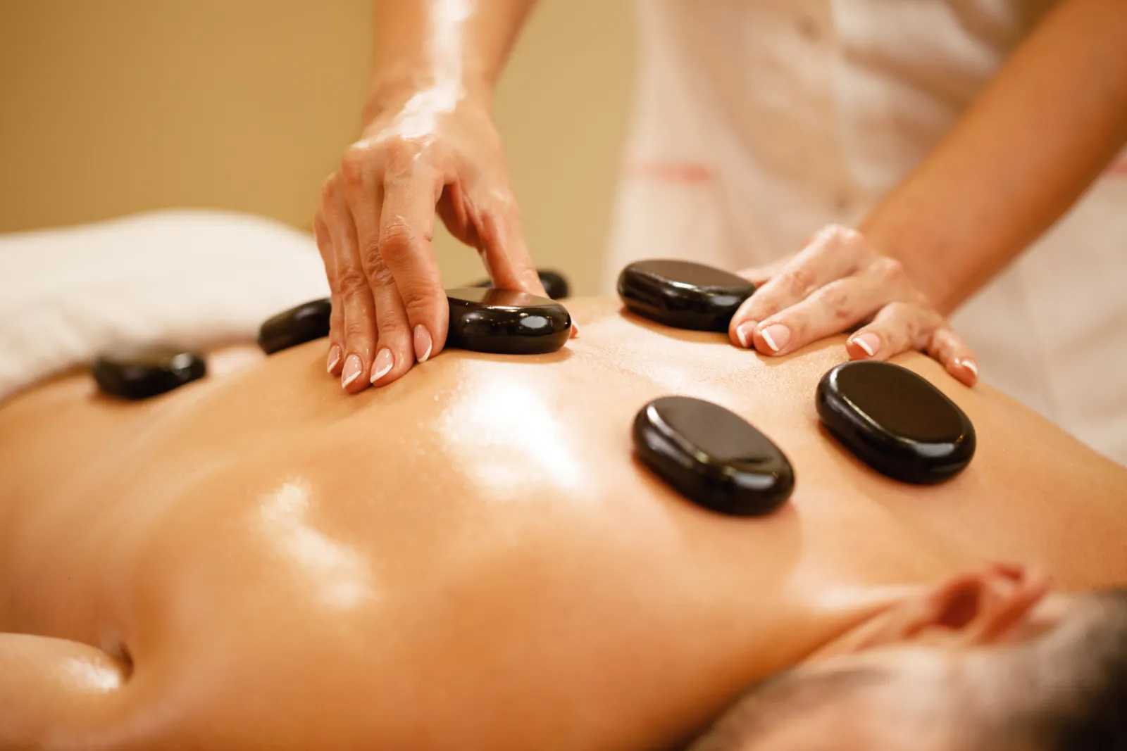Therapist placing hot stones during a surf massage in Bali